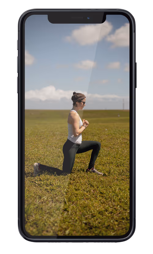 Remote running coach Abby of Wild Dog Athletics performs exercises in a field before trail running as seen on an iphone.