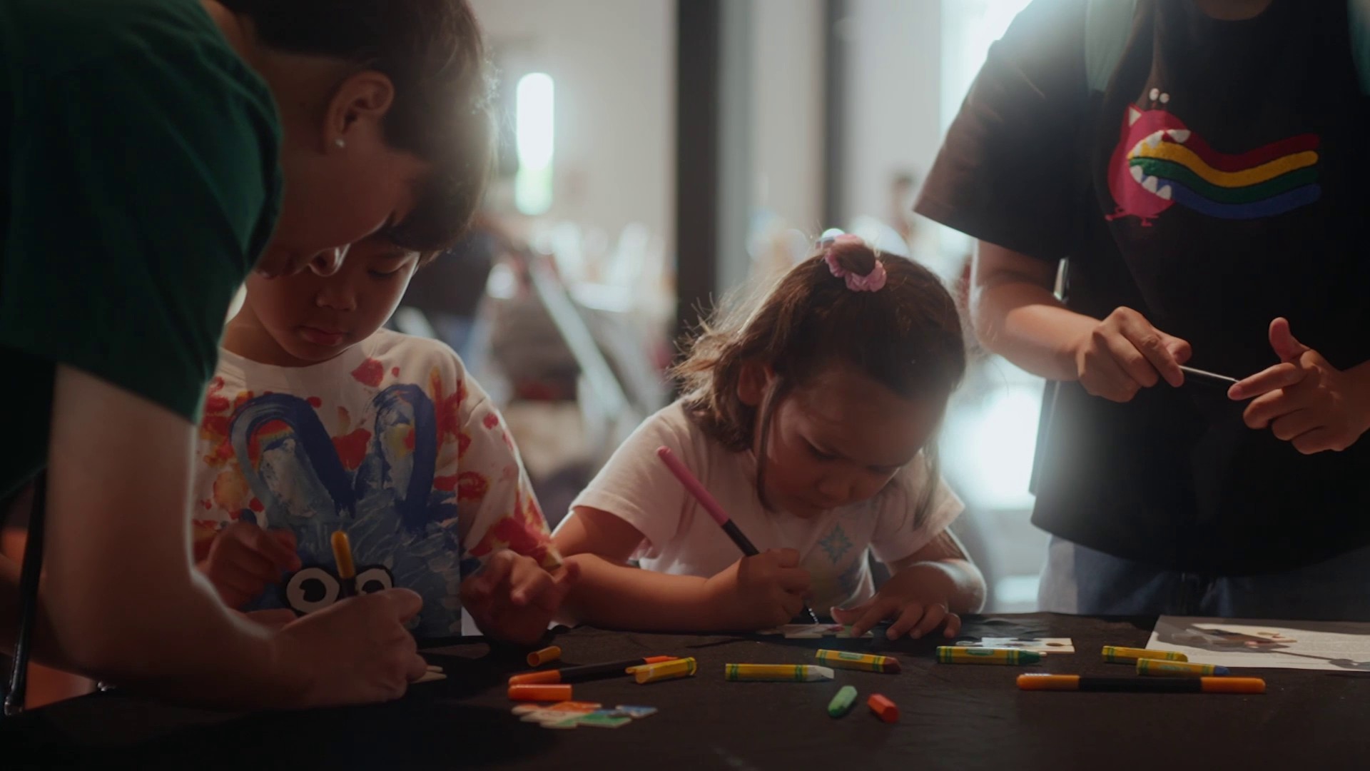 Des enfants sont assis à une table et dessinent, entourés de matériel d’artistes.