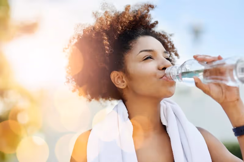 Woman hydrating with a water bottle.