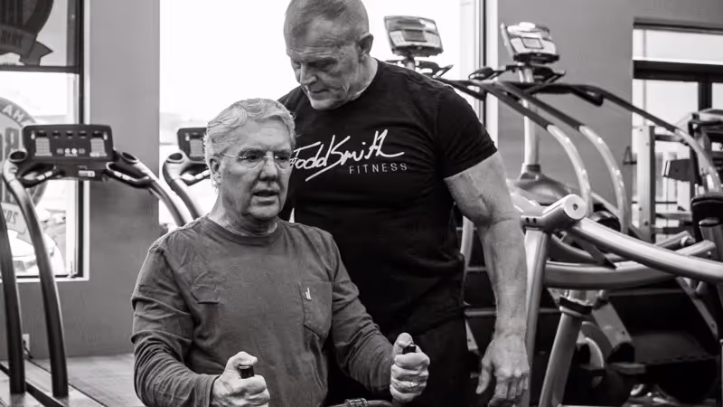 Todd Smith helps a client lift weights in the gym