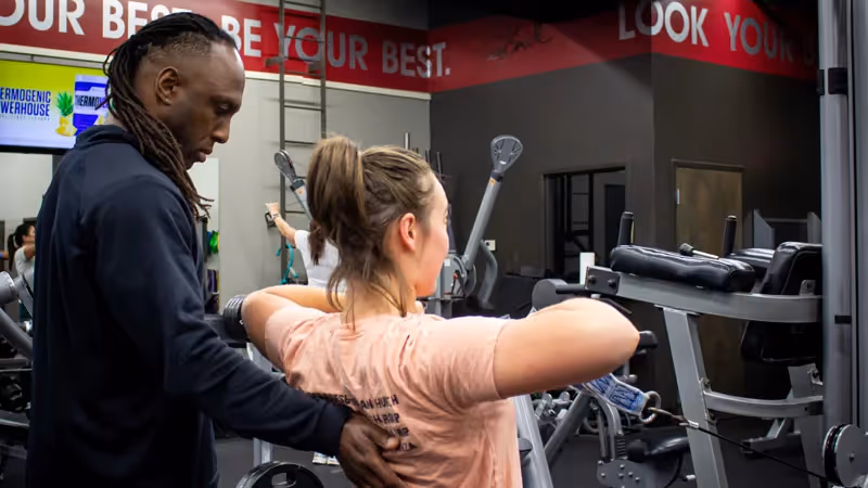 personal trainer at Todd Smith Fitness assisting a customer exercising at the gym