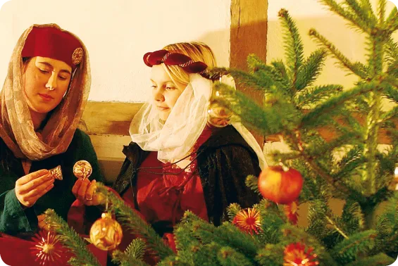 Kvinder i folkedragter pynter et juletræ