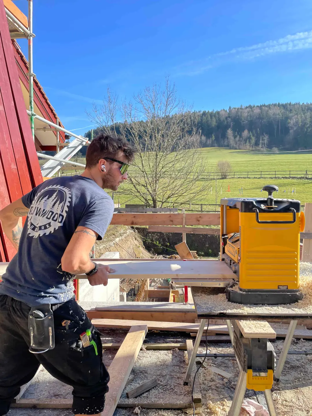 Zimmermann von Flow Wood hobelt ein Brett auf der Baustelle
