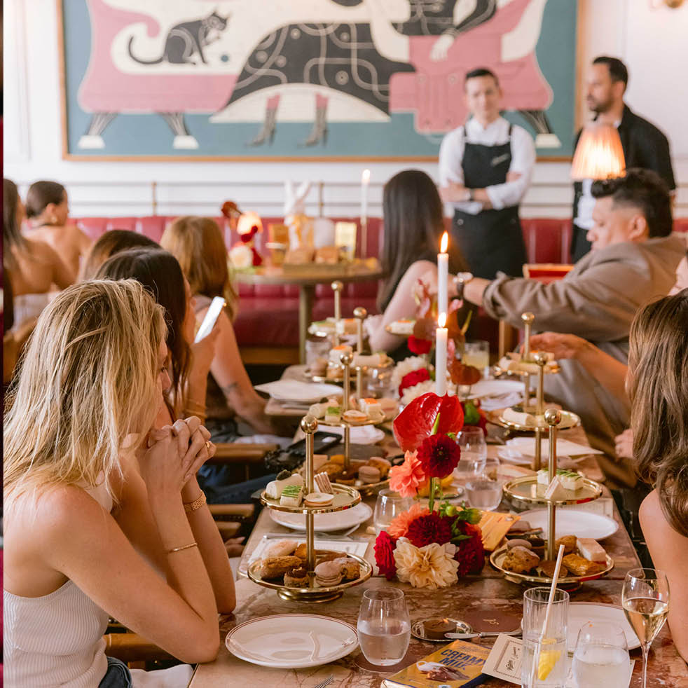 Group dinner at a long table beneath the mural at Armorica, ideal for celebrations in Sydney