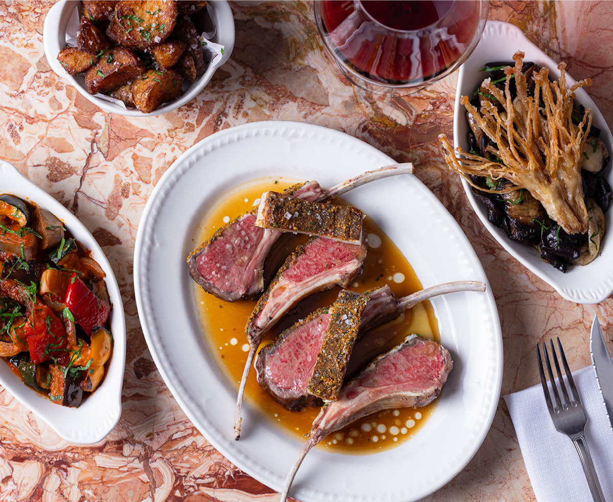 Sliced lamb rack cooked pink with jus and seasonal sides, a signature dish at Armorica French brasserie in Sydney