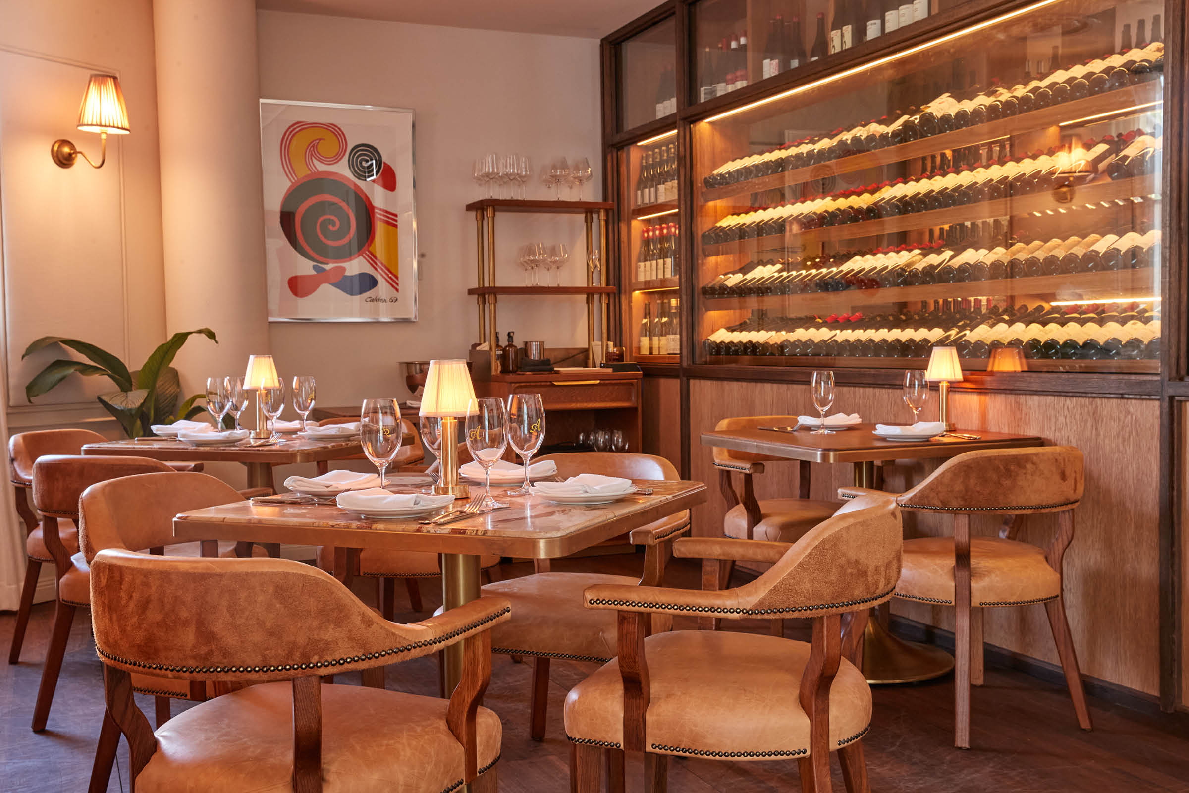 Warm evening private dining room at Armorica with leather chairs, table lamps and a full height wine display