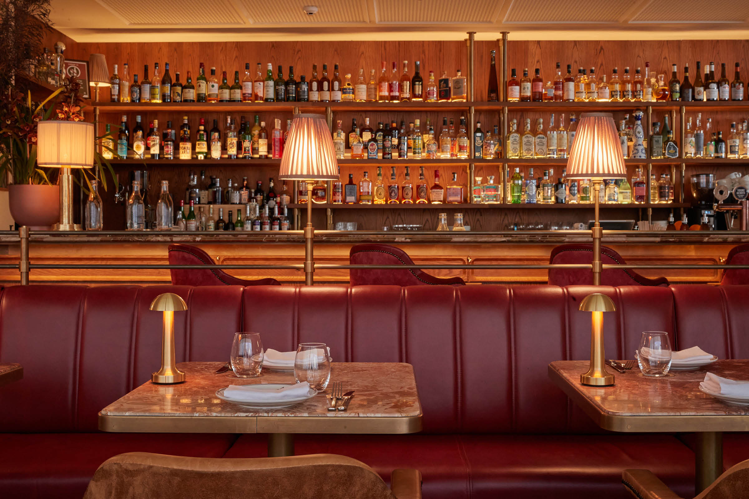 Red leather banquette seating facing the backlit bar at Armorica Grande Brasserie, Sydney
