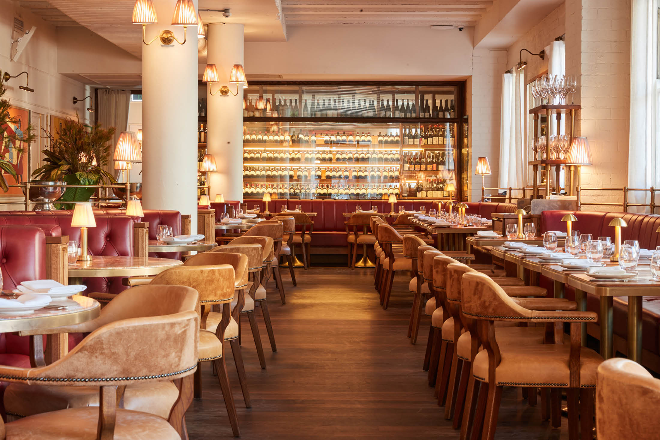 Elegant dining room at Armorica Grande Brasserie in Surry Hills, with red banquettes, white columns and a backlit wine wall