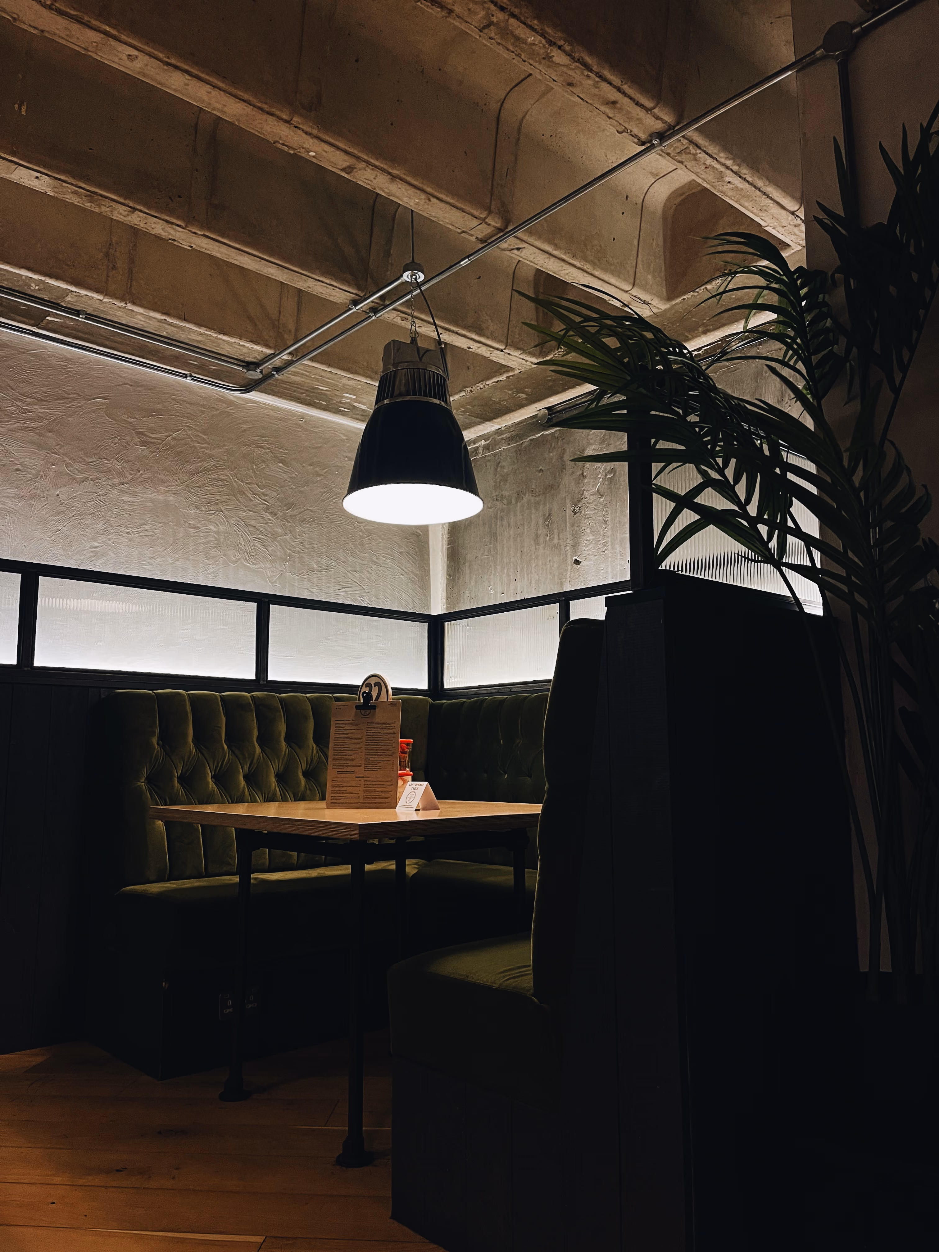 A velvet booth lit by a pendant lamp at Ezra & Gil Peter Street