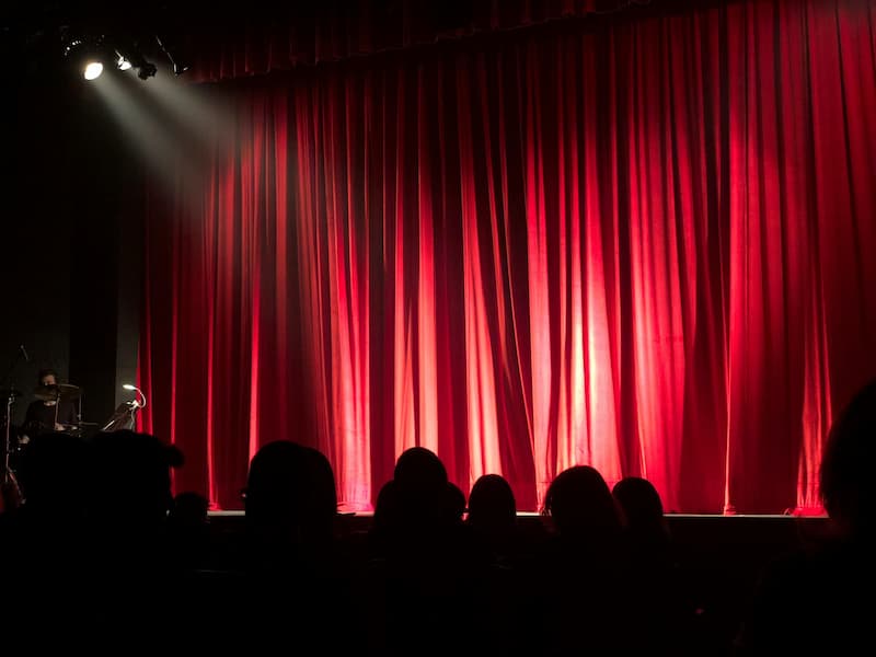Bühne mit rotem geschlossenen Vorhang: Die Show kann gleich losgehen