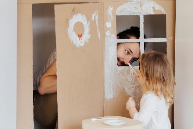 Ein Vater spielt fröhlich mit seinem Kind im Kinderzimmer. Wer ist Gott? Gott zeigt sich als liebevoller Vater, der Zeit mit seinen Kindern verbringt, Nähe schenkt und Freude teilt.