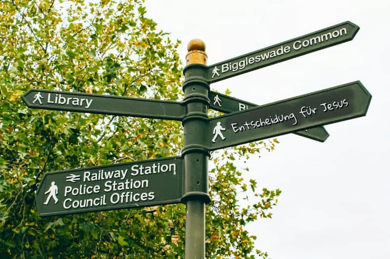 Straßenschild mit fünf Pfeilen in verschiedene Richtungen, eines zeigt auf ‚Entscheidung für Jesus‘, Symbol für bewusste Entscheidung für Jesus Christus