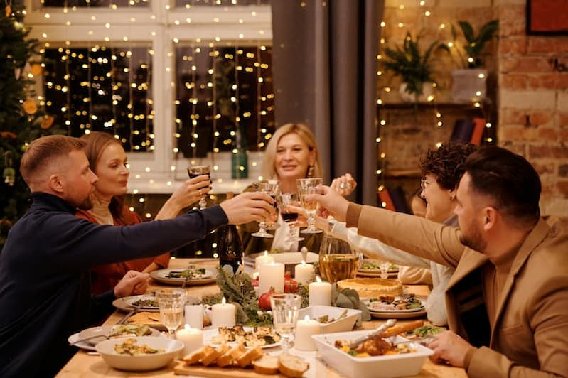 Familie sitzt am reich gedeckten Tisch beim Weihnachtsessen – zeigt die heutige Realität von Weihnachten Wahrheit: Konsum oder Tradition.