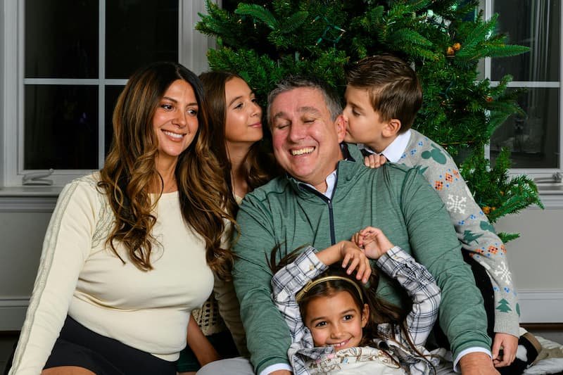 Glückliche Familie steht vor dem Weihnachtsbaum, passend zum christlichen Weihnachtslied "O du fröhliche"