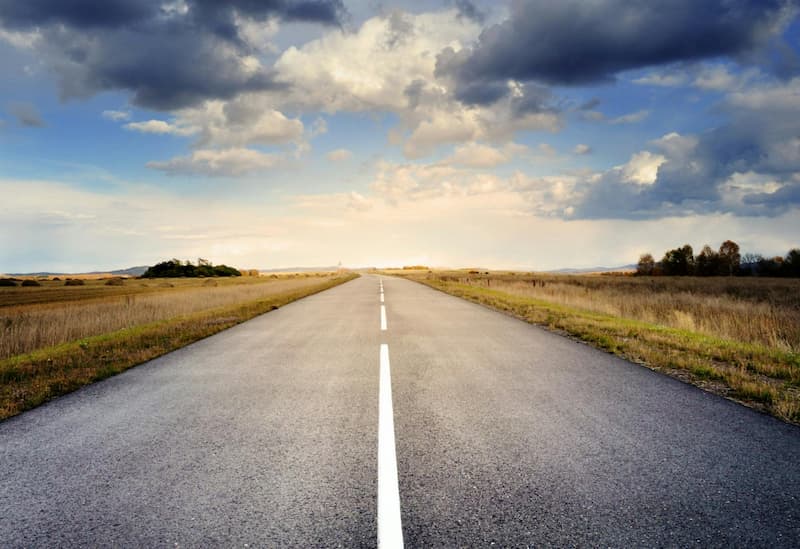 Lange Straße führt zu hellem Licht am Horizont als Symbol für Hoffnung und Sinn im Leben