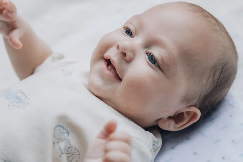 Ein lächelndes Baby liegt mit offenen Augen auf dem Rücken und streckt die Arme in die Höhe – ein Symbol dafür, dass Gott uns nach Psalm 139,13–16 erdacht und geschaffen hat.