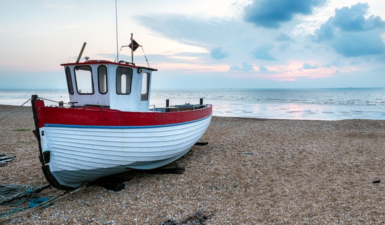 A red and white fishing boat on the beach.