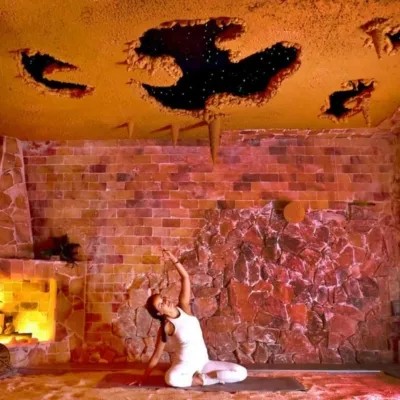 Woman doing yoga on a yoga mat on a salt-covered floor in a salt cave at the Healing Salt Cave & Wellness Spa - Guilford, Connecticut.