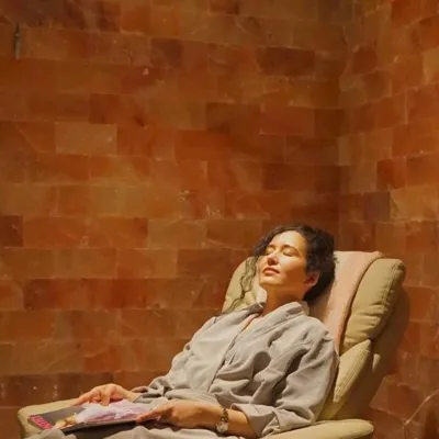 Woman relaxing on a chair in front on a Himalayan salt panel wall at the Art of Balance Wellness Spa - Baltimore, Maryland.