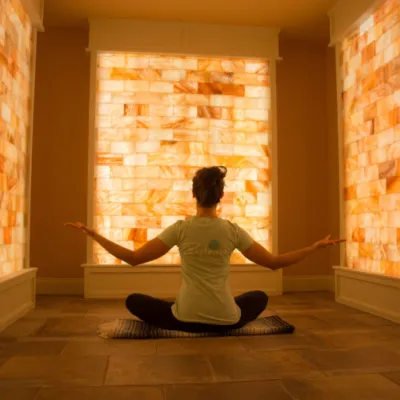 Woman sitting on a blanket on a tile floor surrounded by LED backlit salt panels at the Release Well-Being Center - Westbourough, Massachusetts.