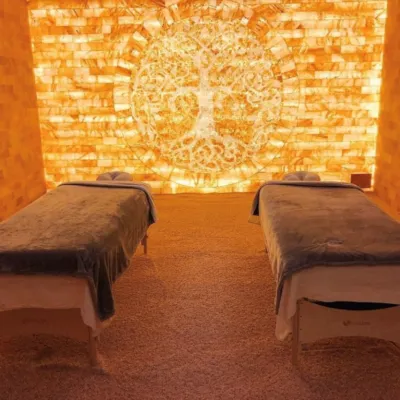 A salt room with two massage tables in front of a Himalayan salt wall.