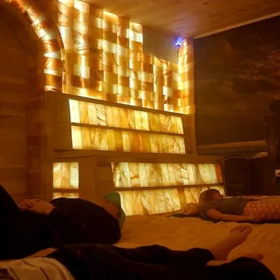 The Salt Cave at Synchronicities Sandy, Utah Three people laying on a salt covered floor in a dim room with salt bricks on the walls