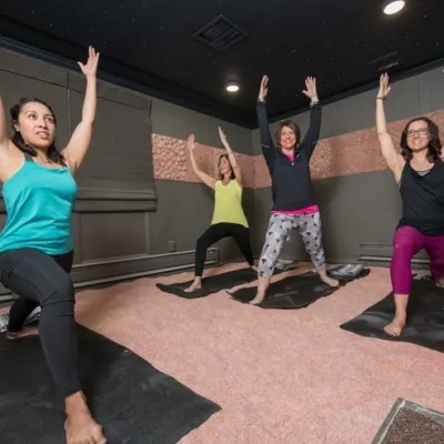 Three women on black yoga mats doing yoga on a salt-covered floor at The Salt Lounge - Wyomissing, PA.