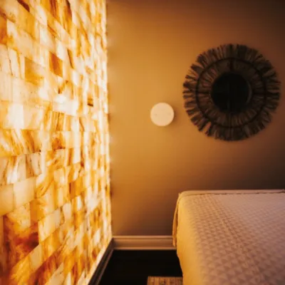 A salt therapy room at The Woodhouse Days Spa in Dallas, Texas with a massage table, Himalayan salt brick wall and a halogenerator on the wall.