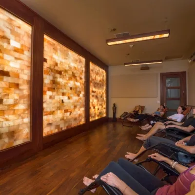 Two men and four women relaxing in lounge chairs facing a LED backlit salt stone wall.