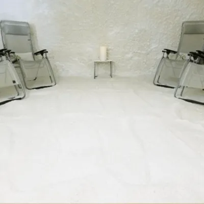 A white salt-covered floor with white salt walls and four reclining chairs at the Fusion Therapy in Sarasota, Florida