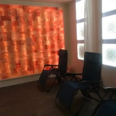 Three reclining chairs on a brown vinyl flooring with a LED backlit salt stone wall Gemini Salt Spa in Merriam, Kansas