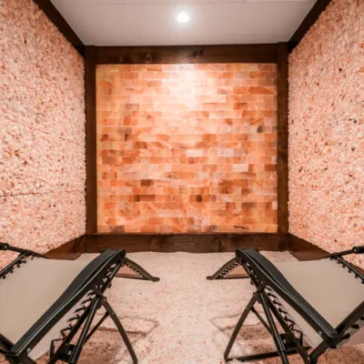 Two reclined chairs on a salt covered floor surrounded by salt stone walls and a paneled Himalayan salt stone wall.