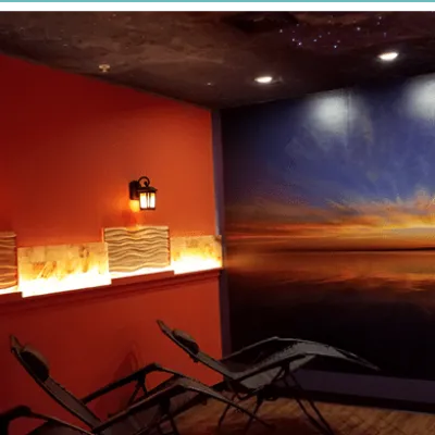 Two reclined chairs facing a sunset decor wall in an salt therapy room at Just Breathe Salt Spa in Hyannis, Massachusetts