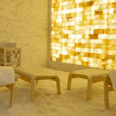Natural Healing Day spa. Brightly lit salt room with white salt. Three lounge chairs sit inside of the room.