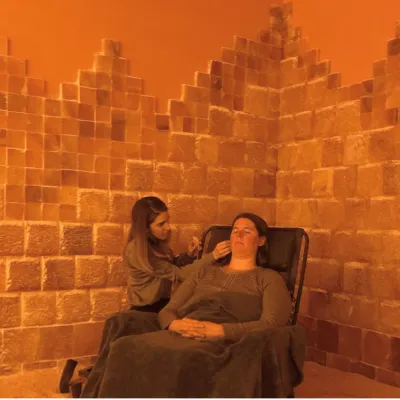 Prana Salt Cave. Woman laying back in chair in salt cave while receiving a skin treatment