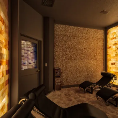 Pura Vida Body and Mind Spa. Two lounge chairs in dimly lit salt room up against tile wall.
