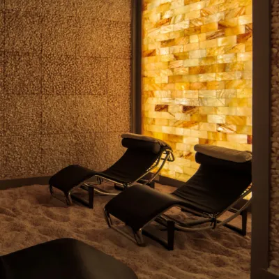 Pura Vida Body and Mind Spa. Two lounge chairs in dimly lit salt room up against tile wall.