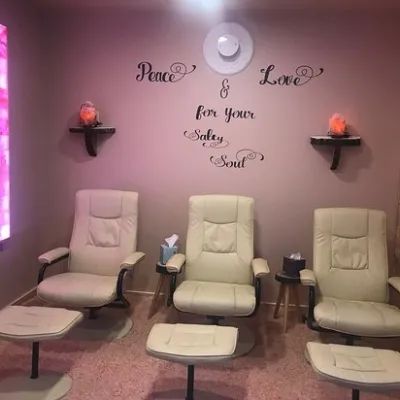 Three tan chairs with ottomans in a room with a magenta colored LED backlit salt panel on one side and a yellow LED backlit salt panel on the other side of the room
