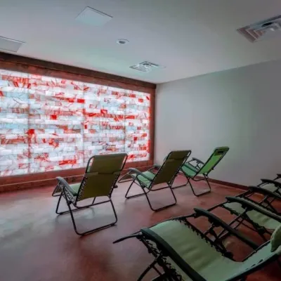 Salt and Spa. 6, green lounge chairs lined up facing a blue, white and red lit salt wall.