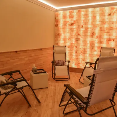 Four lounge chairs facing each other in a room with a himalayan salt brick wall in the background at The Salt Barre in Pittston, Pennsylvania