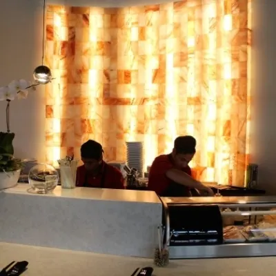 Four men making food in front of a backlit salt paneled wall at the Red Salt Chophouse.