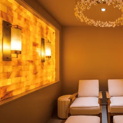Two lounge chairs in salt room with chandelier overhead and a salt wall on the left at Addison Reserve Country Club in Delray Beach, Florida