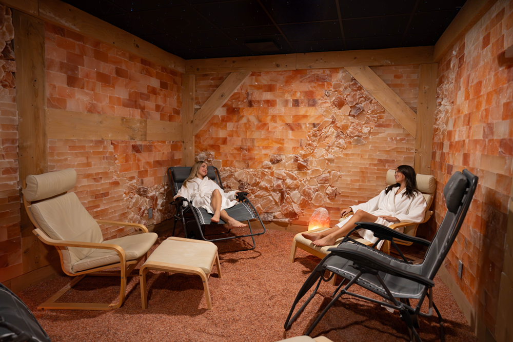 An editorial showroom from SALT Chamber in Boca Raton FL display comparing a backlit orange salt brick wall with textured pink and white salt panels next to a modern conference table.