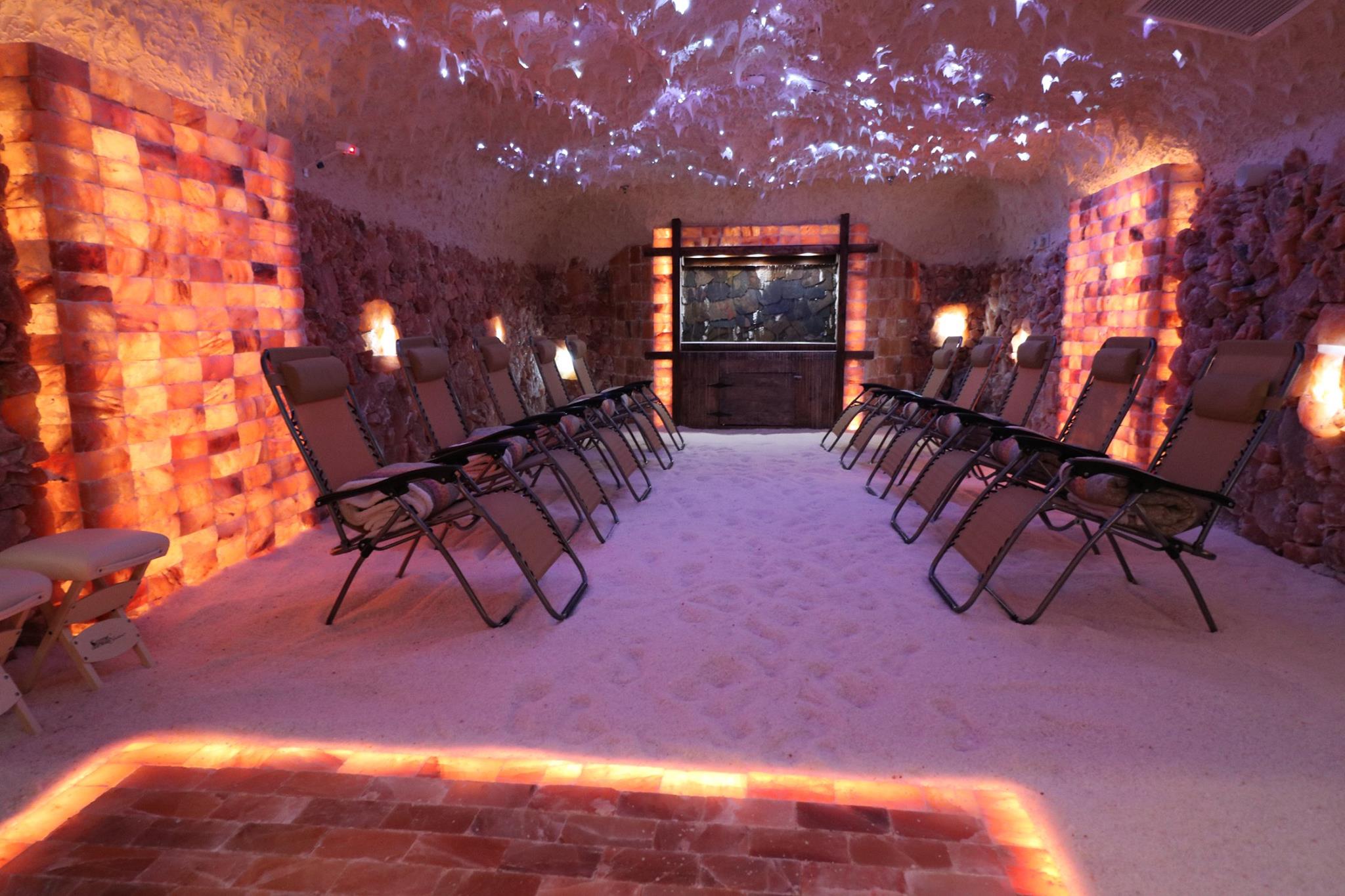 An editorial showroom from SALT Chamber in Boca Raton FL display comparing a backlit orange salt brick wall with textured pink and white salt panels next to a modern conference table.