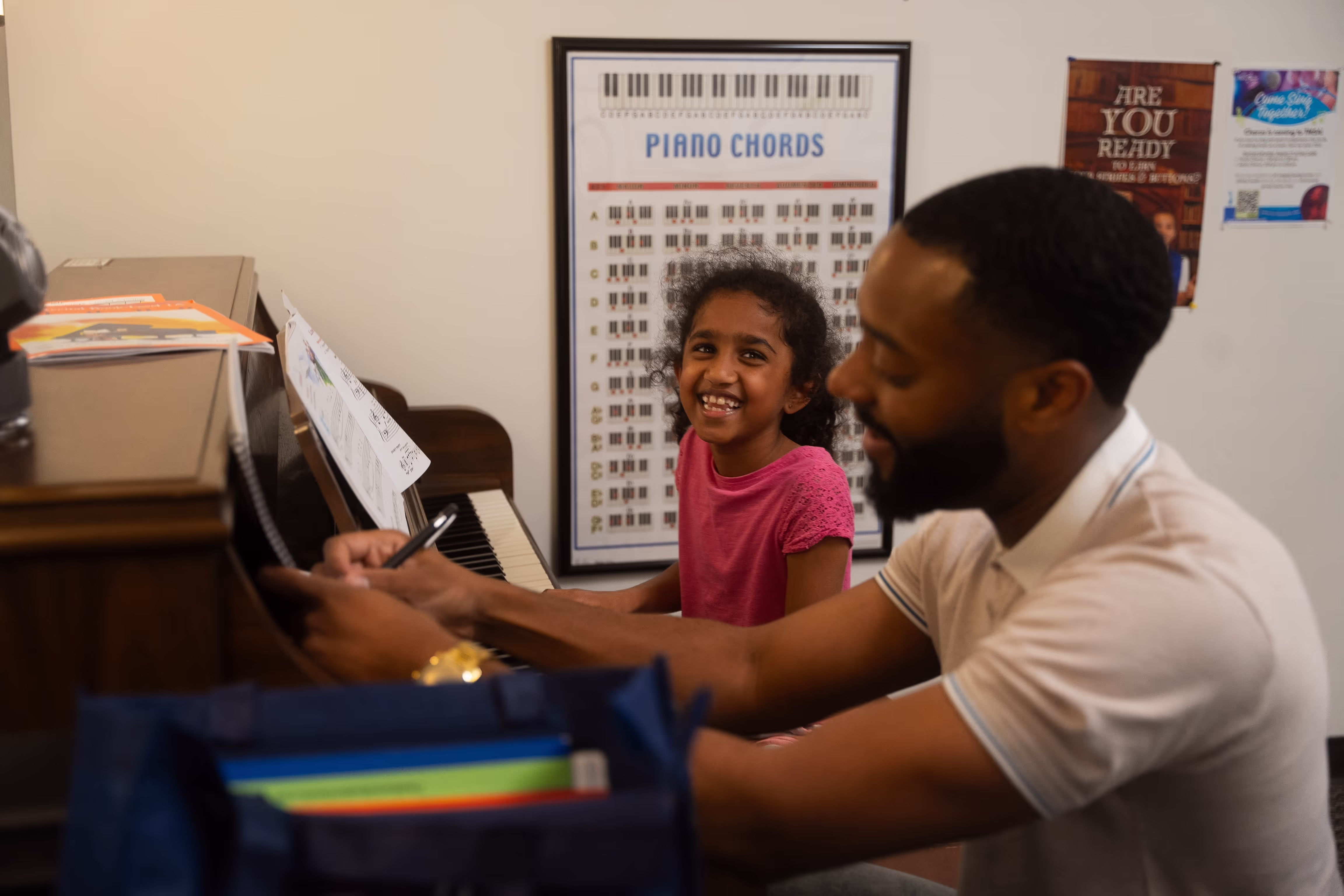 Student and instructor setting up for a piano lesson in a comfortable, well-lit studio.
