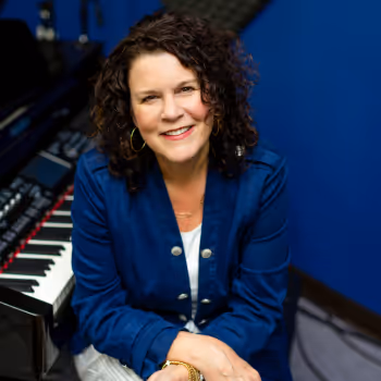 A photo of Cecilia Rowe, the Director and CEO of The Music Studio Atlanta, smiling while sitting in front of a piano.