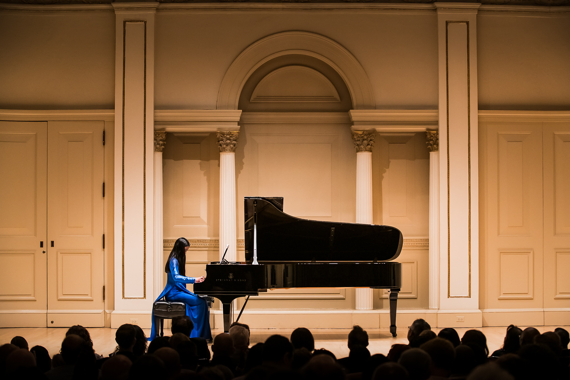 Girl in blue dress performing Piano in Carnegie Hall in New York City.