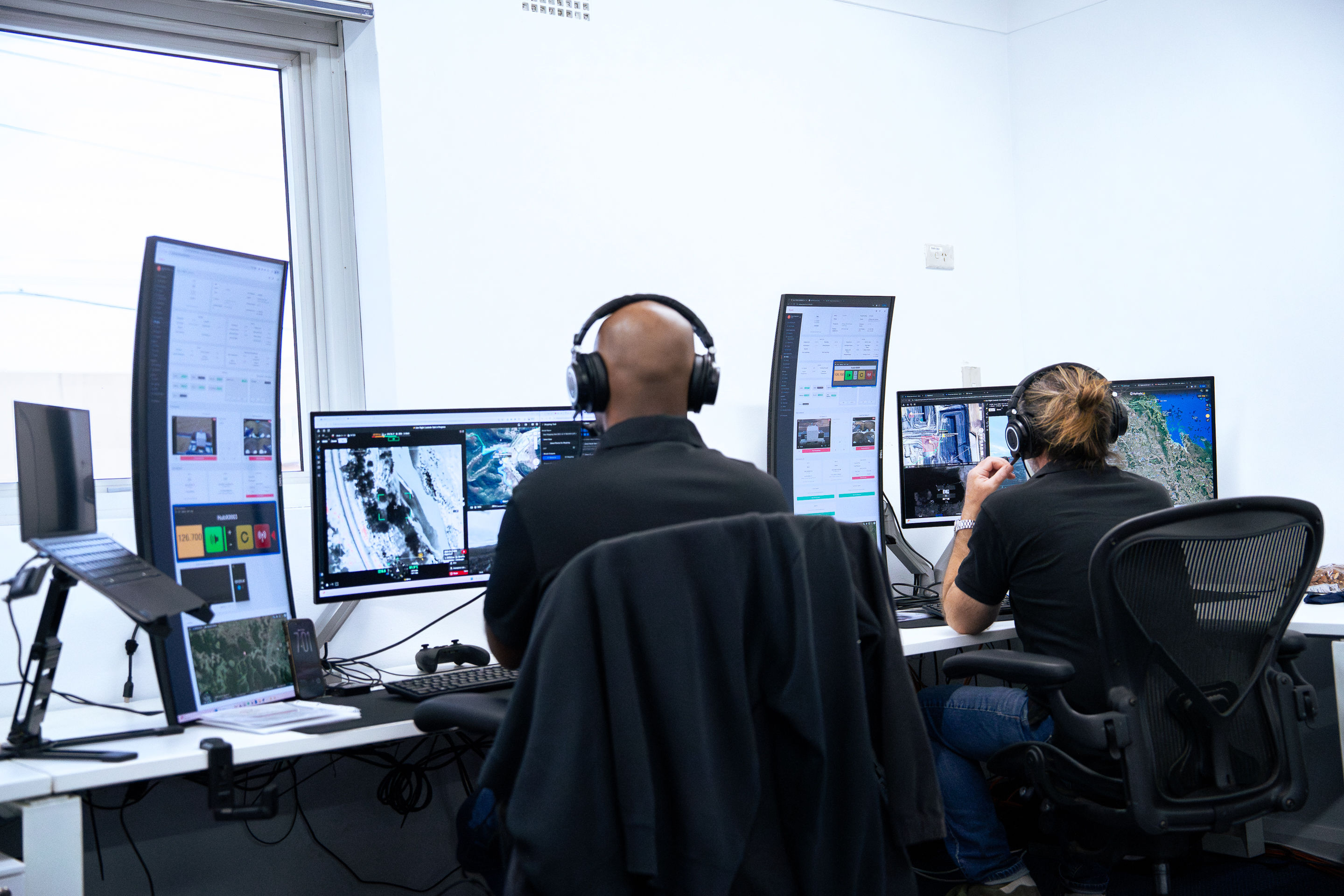 Two Sphere remote pilots on shift in the Remote Operations Centre, with every station live