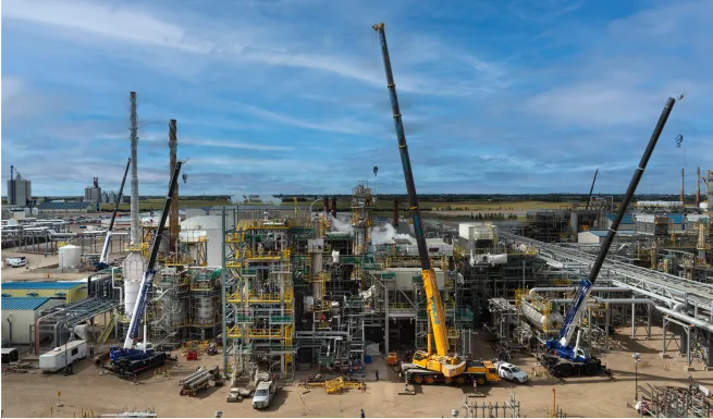 a large industrial plant with cranes and other equipment in the foreground