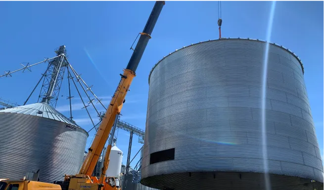crane lifting a large metal tank into the air